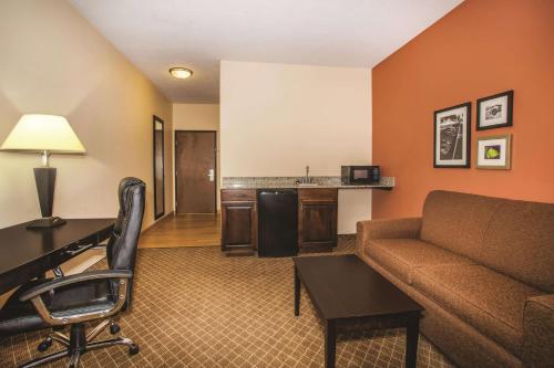 a living room with a couch and a desk in a hotel room at La Quinta by Wyndham Ely in Ely