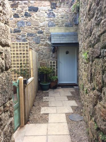 um edifício de pedra com uma porta azul e uma cerca em Wrenscott em Chagford