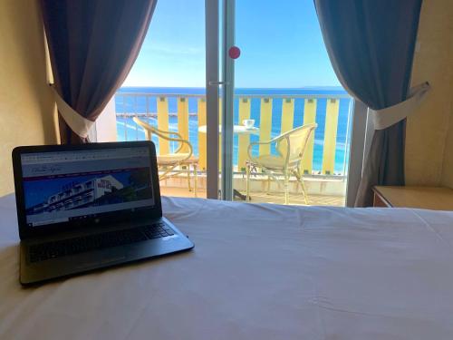 a laptop on a bed in a room with a balcony at Le Beau Séjour in Saint-Raphaël