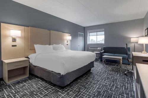 ein Hotelzimmer mit einem großen Bett und einem Stuhl in der Unterkunft Comfort Inn Hyannis - Cape Cod in Hyannis