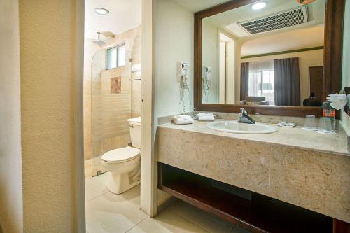 W łazience znajduje się umywalka, toaleta i lustro. w obiekcie Quality Inn Ciudad Obregon w mieście Ciudad Obregón