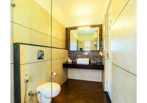 a bathroom with a toilet and a mirror at MySpace Express Oleander Service Apartments in Madikeri
