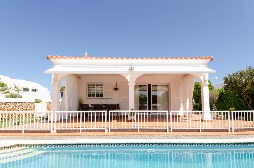 a white house with a pool in front of it at VILLA ANA ARENAL D'en CASTELL in Es Mercadal