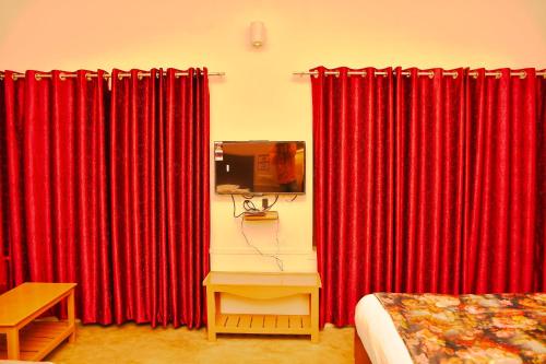 a room with red curtains and a bed and a table at Gobind Bhawan Heritage Hotel in Haridwār