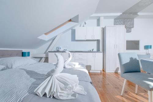 a white bedroom with a bed and a blue chair at OŚRODEK KOLONIJNO WCZASOWY MEWA - przy plaży z basenem z podgrzewaną wodą i mini SPA in Niechorze