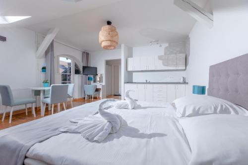 a white bedroom with white swans on the bed at OŚRODEK KOLONIJNO WCZASOWY MEWA - przy plaży z basenem z podgrzewaną wodą i mini SPA in Niechorze