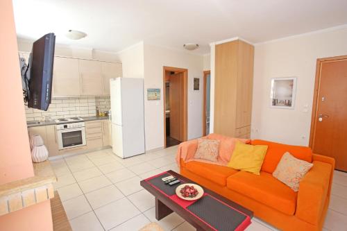 een woonkamer met een oranje bank en een keuken bij Apartment near the sea and the Athens airport , Artemida in Artemida