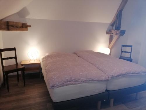 Montpont-en-Bresse的住宿－La Grange à outeaux，一张位于带两盏灯和一把椅子的房间的床铺