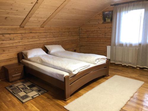 a bed in a wooden room with a window at Вербовий двір - Willow Yard in Zhdenievo
