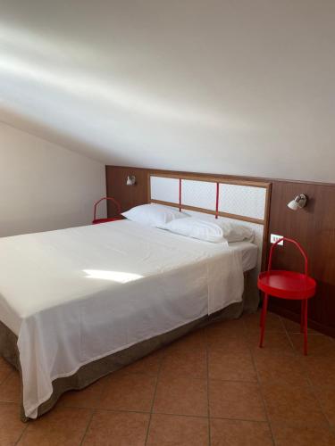 1 dormitorio con 1 cama blanca y 1 silla roja en Carolina Apartments - Mansarda, en Capo dʼOrlando
