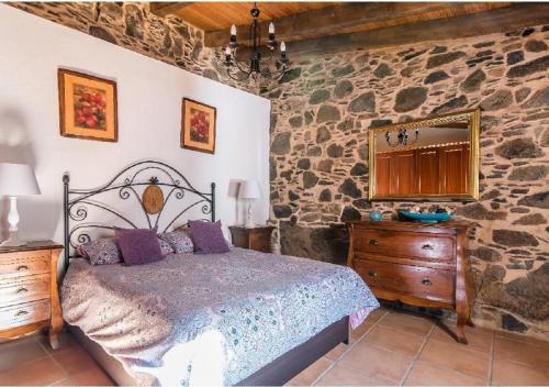 a bedroom with a bed and a stone wall at Casa Agustín Pool 27 ºC in Fátaga