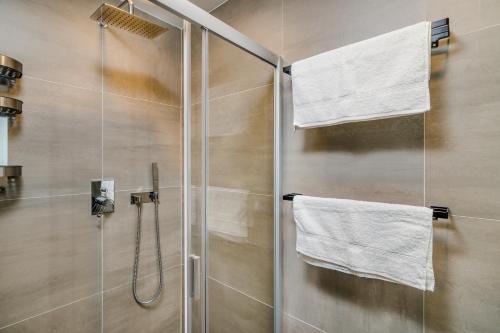 une douche avec des serviettes blanches sur une porte vitrée dans l'établissement Prague Days - Premium Loft w Terrace - View - Netflix - AC, à Prague