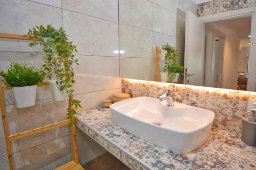 a bathroom with a sink and a potted plant at Potamos Deluxe White Apartment in Potamós