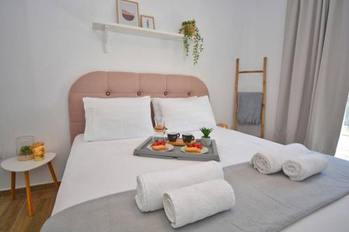 a bed with a tray of fruit on it at Potamos Deluxe White Apartment in Potamós