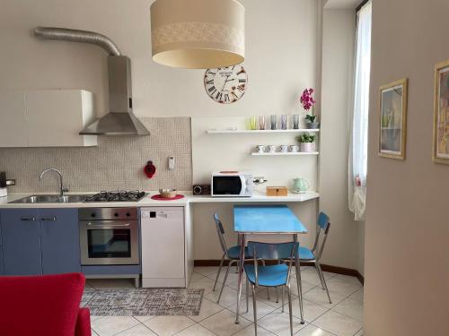 cocina con fregadero y mesa con sillas azules en Appartamento “Liberty” en Paderno Dugnano