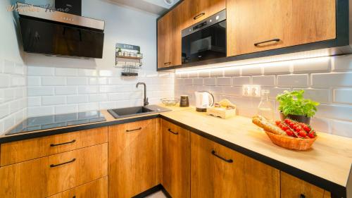 a kitchen with wooden cabinets and a basket of fruit on a counter at Wonder Home - Apartamenty położone blisko deptaka, licznych restauracji i sklepów in Karpacz