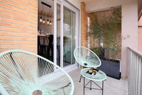 2 weiße Stühle und ein Tisch auf der Terrasse in der Unterkunft expat renting - Les Oustalous - Piscine - Parking in Toulouse