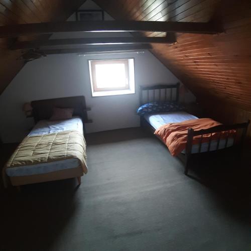 deux lits dans une chambre mansardée avec une fenêtre dans l'établissement Chez Grand-Mère, à Le Monteil