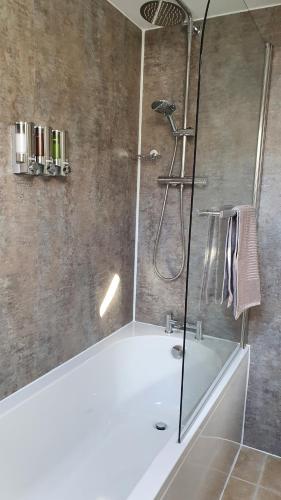 a bathroom with a shower with a white tub at Liongate House in Ilchester