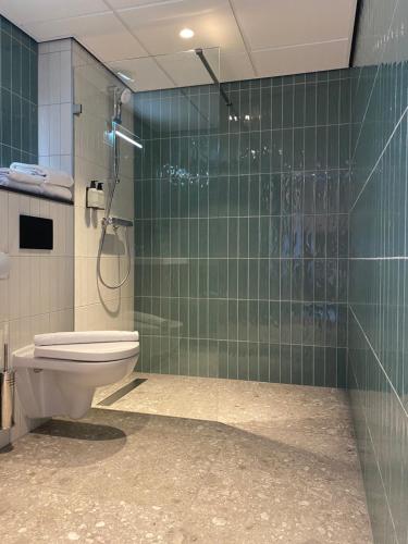 ザーンデイクにあるBoutique Hotel Zaanの緑のタイル張りの壁、トイレ付きのバスルーム