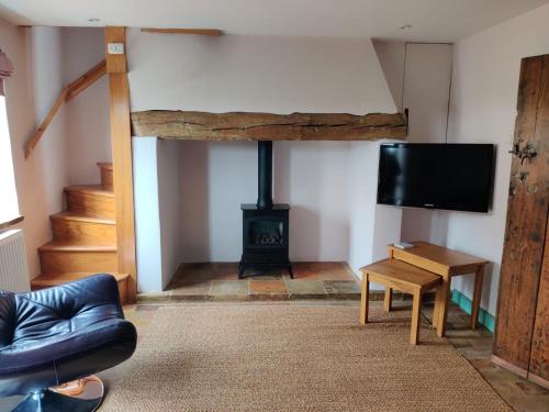 a living room with a fireplace and a flat screen tv at Alicias Cottage, Bacton in Norwich
