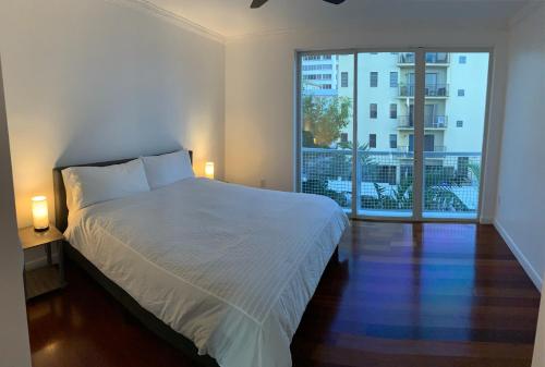 a bedroom with a white bed and a large window at Capri in Miami Beach