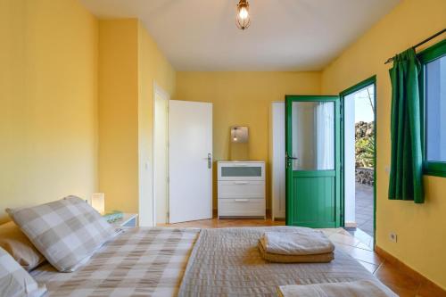 a bedroom with yellow walls and green doors and a bed at Casa Uva in Yaiza