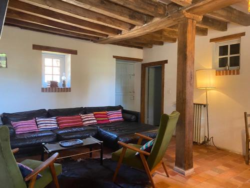 - un salon avec un canapé et des fauteuils en cuir noir dans l'établissement Cottages et B&B de Troussay, à Cheverny
