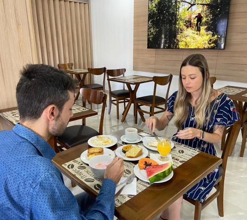 Un uomo e una donna seduti a tavola mangiando cibo di Hotel Confort a Mafra