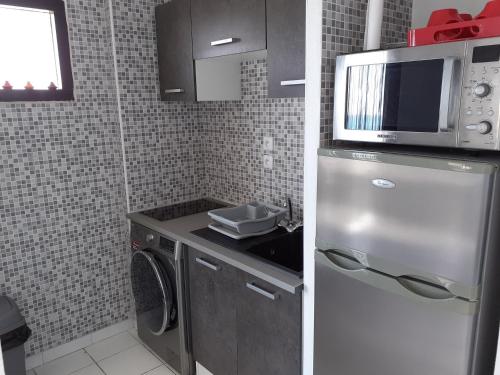 une petite cuisine avec un micro-ondes et un réfrigérateur dans l'établissement Appartement 1ère ligne très belle vue mer Rochelongue Cap d'Agde, au Cap d'Agde