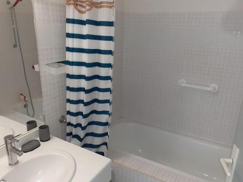 une salle de bain avec un lavabo et un rideau de douche dans l'établissement Appartement 1ère ligne très belle vue mer Rochelongue Cap d'Agde, au Cap d'Agde