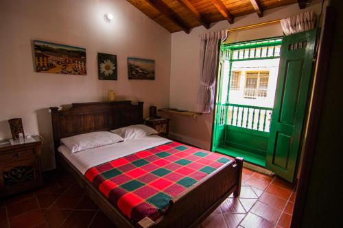 a bedroom with a bed and a green window at Hotel Cacique Chalalá in Charalá