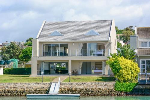 a house on the water with a stone wall at The Holy Hill Royal Alfred Marina in Port Alfred