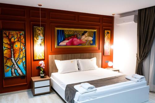 1 dormitorio con 1 cama con una pintura en la pared en Jata Crown Hotel en Tirana