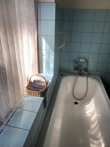 a bathroom with a bath tub with a window and a basket at Retro bolig - fyldt med hygge! Ingen luksus in Kolind