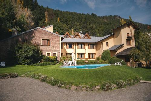 une grande maison avec une piscine dans la cour dans l'établissement Hosteria Las Lengas, à San Martín de los Andes