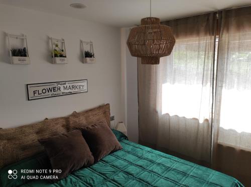 a bedroom with a bed with a green comforter and a window at Malpica Nordic Home in Malpica