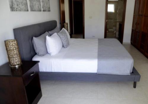 a bedroom with a large white bed with a night stand at Bavaro Punta Cana Apartamento con Piscina in Punta Cana