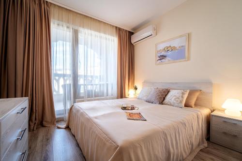 Un dormitorio con una cama grande y una ventana grande. en Summertime in Varna South Bay Beach Residence, en Varna