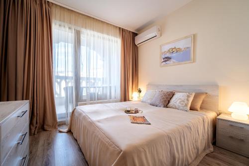 a bedroom with a large bed and a large window at Summertime in Varna South Bay Beach Residence in Varna City
