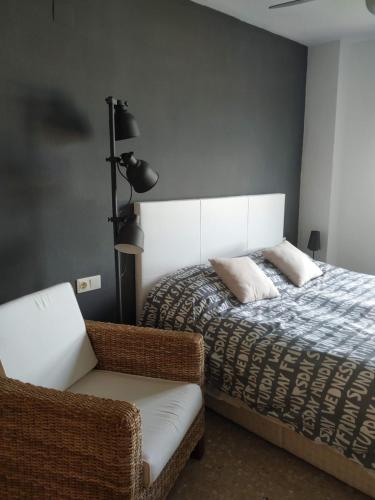 ein Schlafzimmer mit einem Bett und einem Stuhl in der Unterkunft Apartamento Con Preciosas Vistas Al Mar,WIFI y piscina de temporada in Canet d'en Berenguer