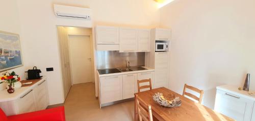 una cocina con armarios blancos y una mesa en una habitación en Affittacamere La Fonte, en Levanto