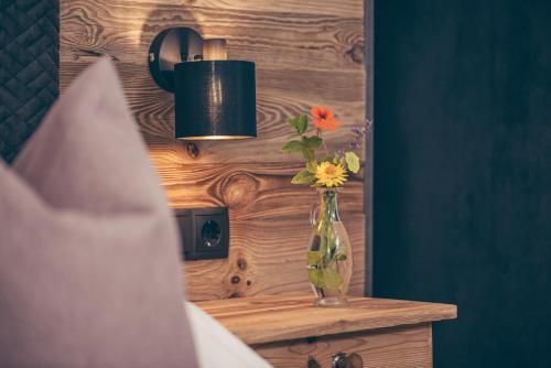 a vase with flowers on a table in a bedroom at Gästehaus die geislerin in Gerlos