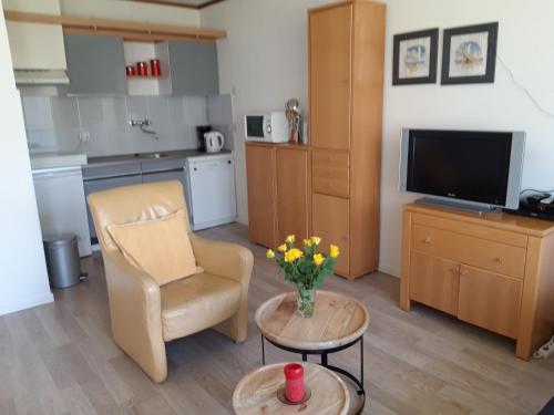 a living room with a chair a table and a television at Duinweg 35 in Westkapelle