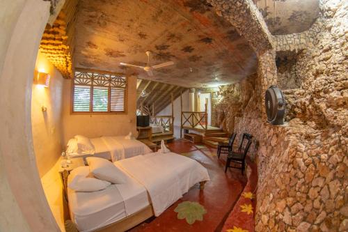 a bedroom with two beds and a stone wall at Paraiso Caño Hondo in Los Guineos Perdidos