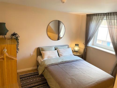 een slaapkamer met een bed met een spiegel en een raam bij Juodkrantes apartamentai in Juodkrantė
