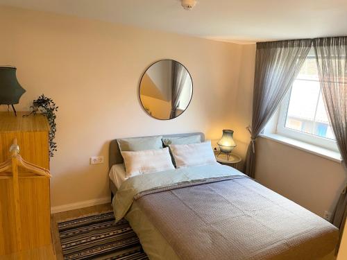 una camera da letto con un letto con uno specchio e una finestra di Juodkrantes apartamentai a Juodkrantė