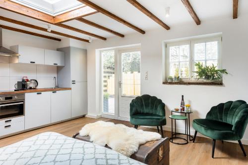 a bedroom with a bed and two green chairs at Cottage 44 - Free parking! in Zandvoort