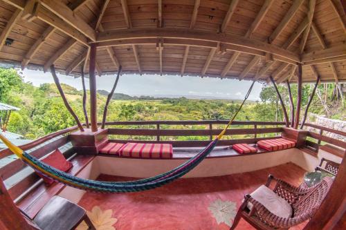 a room with a hammock and chairs on a porch at Paraiso Caño Hondo in Los Guineos Perdidos