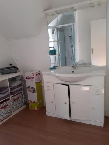 een badkamer met een witte wastafel en een spiegel bij Emeraude - Pause in Pleurtuit